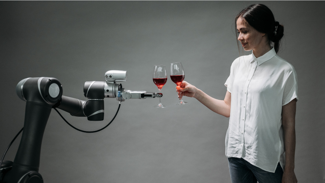 Woman in white shirt interacting with a robotic arm that's holding a glass of red wine, symbolizing the relationship between humans and AI technology as Google's new AI search features transform how businesses connect with customers
