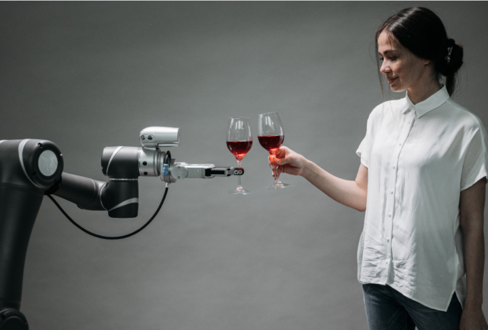 Woman in white shirt interacting with a robotic arm that's holding a glass of red wine, symbolizing the relationship between humans and AI technology as Google's new AI search features transform how businesses connect with customers
