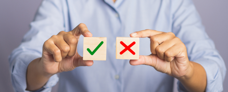 Choice to accept or decline concept wrt GA consent mode v2 deadline - hand of holding two wooden cubes with a check for yes and a cross for no while standing with gray background in the studio - close up photo